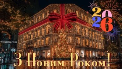 Святкова листівка 2026 року з нічним містом, будівлею, обгорнутою гірляндами й червоною стрічкою, та феєрверками навколо цифр 2026.