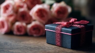 Чорна подарункова коробочка з рожевою стрічкою на фоні троянд — стильне привітання племінниці від тітки.