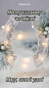 Новорічна листівка для коханого чоловіка з білою блискучою підковою, прикрашеною ялинковими гілочками та вогниками.