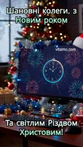 Офісне новорічне привітання для колег із прикрашеним робочим місцем, монітором із годинником і сяючою ялинкою.