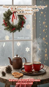 Різдвяний вінок на засніженому вікні та дерев’яний стіл із чайником і двома червоними чашками гарячого напою.