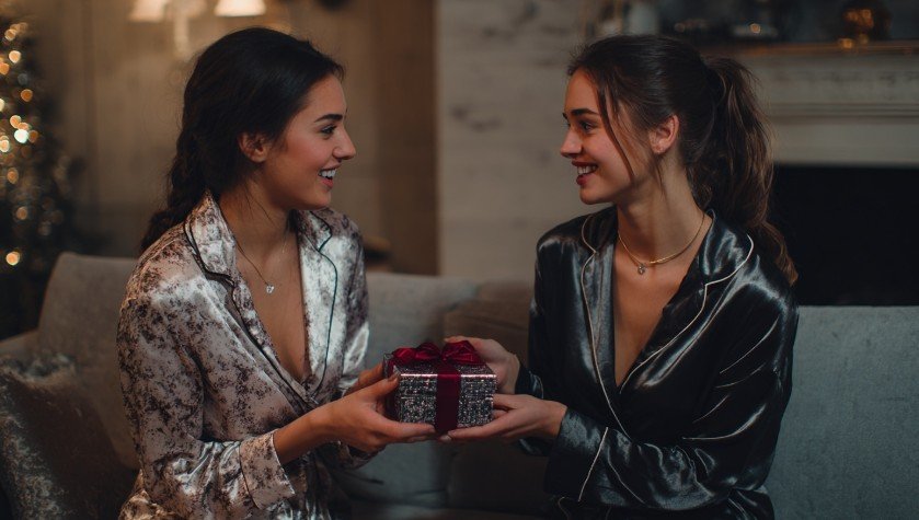 Одна подруга вручає подарунок іншій у затишній кімнаті