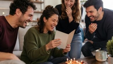 Friends laughing at a funny birthday card during a birthday celebration with cake