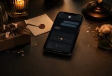 Phone with a late birthday message beside a gift and flower in a dark setting